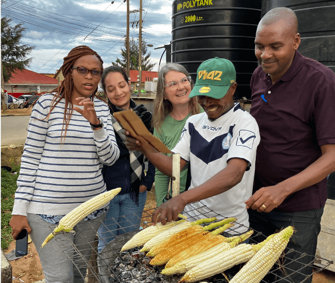 Trying a delicious snack of grilled corn with CARE and World Wildlife Fund colleagues in Iringa, Tanzania.